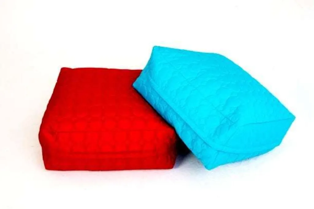 Two child square cotton bean bags with quilted covers, one red and one turquoise, arranged on a white background.