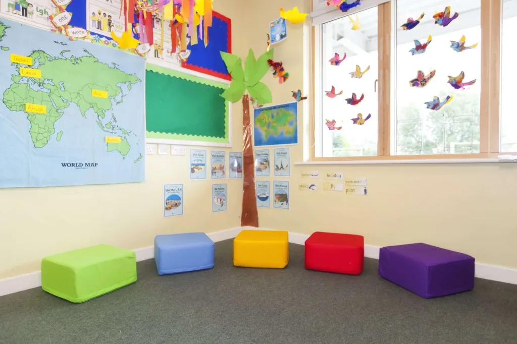 Five square cotton foam seating pods in green, blue, yellow, red and purple arranged on a classroom floor.