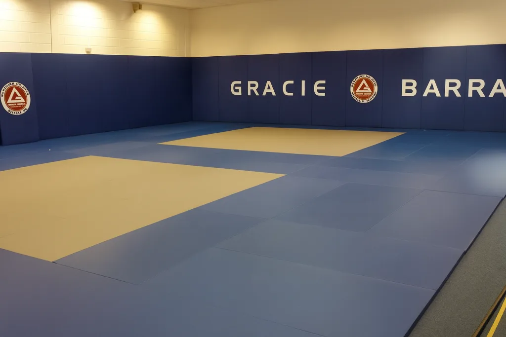 Royal blue training mats with two lighter central mat areas and padded blue wall reading GRACIE BARRA.