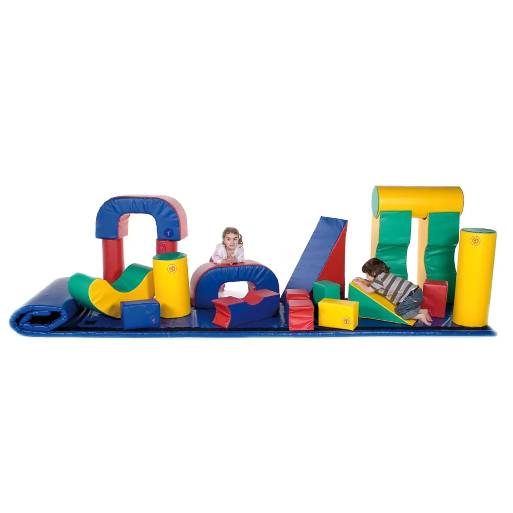 Huge soft-play carpet fitted with hook-and-loop strips and 19 colorful foam shapes (blue, red, yellow, green) arranged as obstacles, two children climbing on them.