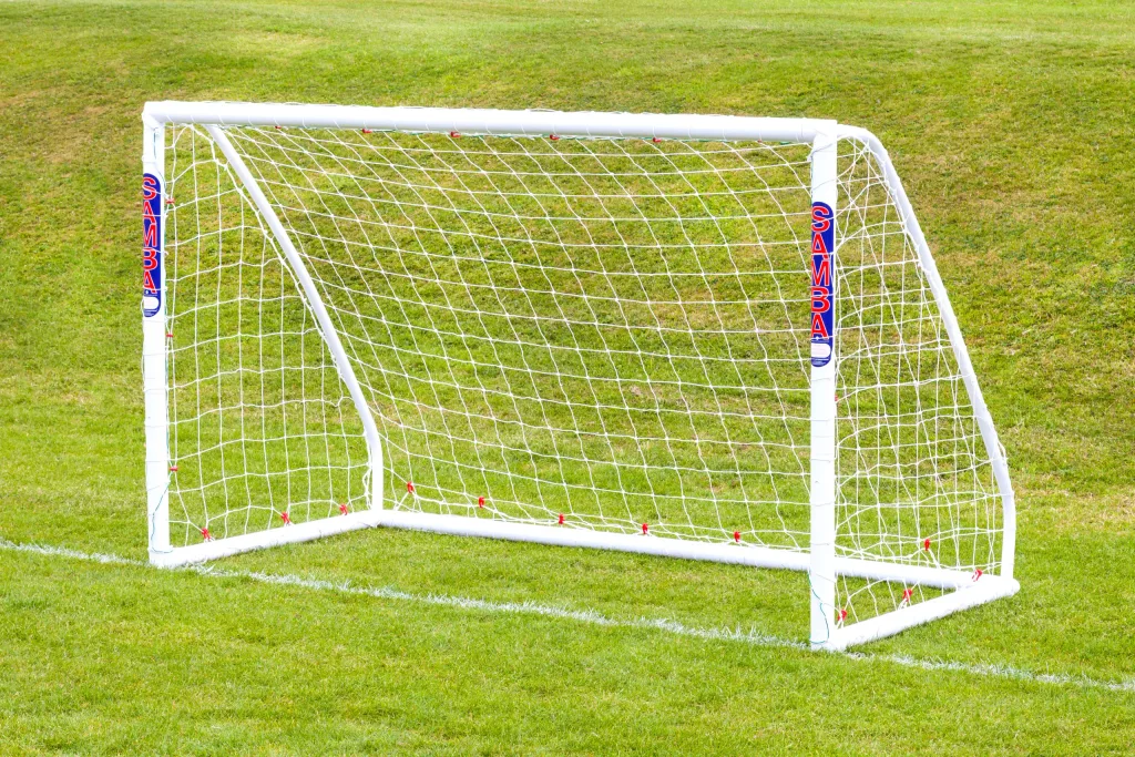 Freestanding uPVC soccer goal with knotted netting, red net ties, and SAMBA labels set on a grass field.