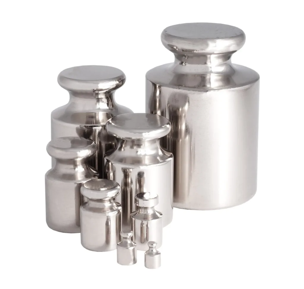 Shiny metal calibration weights grouped by size on a white background.
