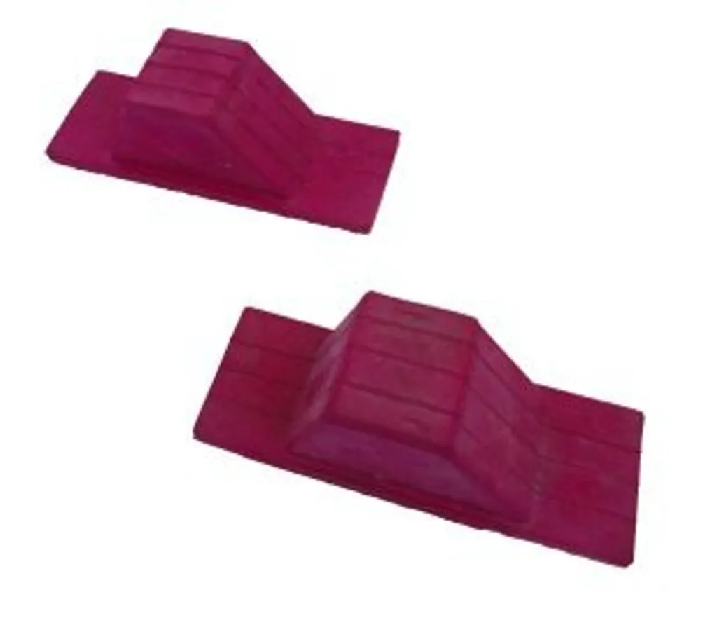 Pair of red rubber starting blocks with ridged wedge shapes, flat bases, and rubber surfaces that grip sports hall floors.