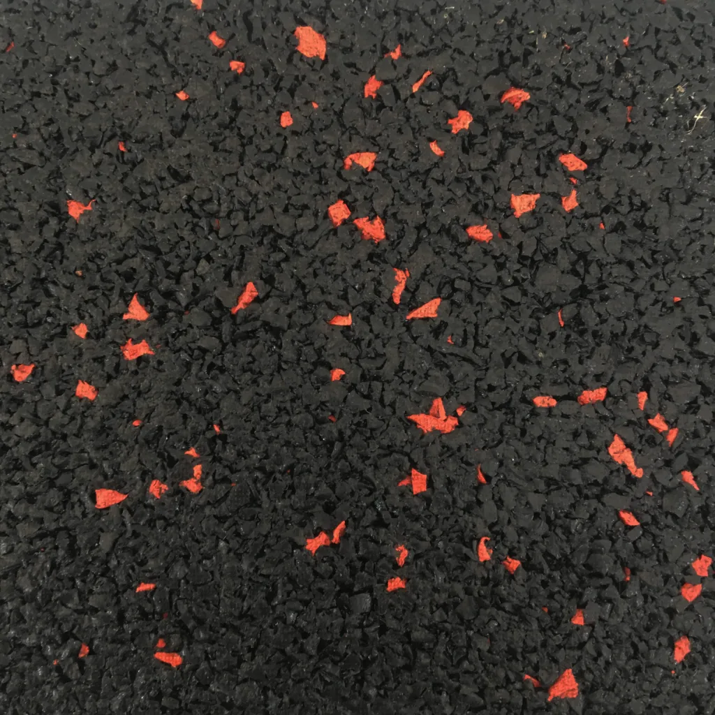 Black rubber flooring with scattered red flecks and a coarse, crumb-like textured surface.