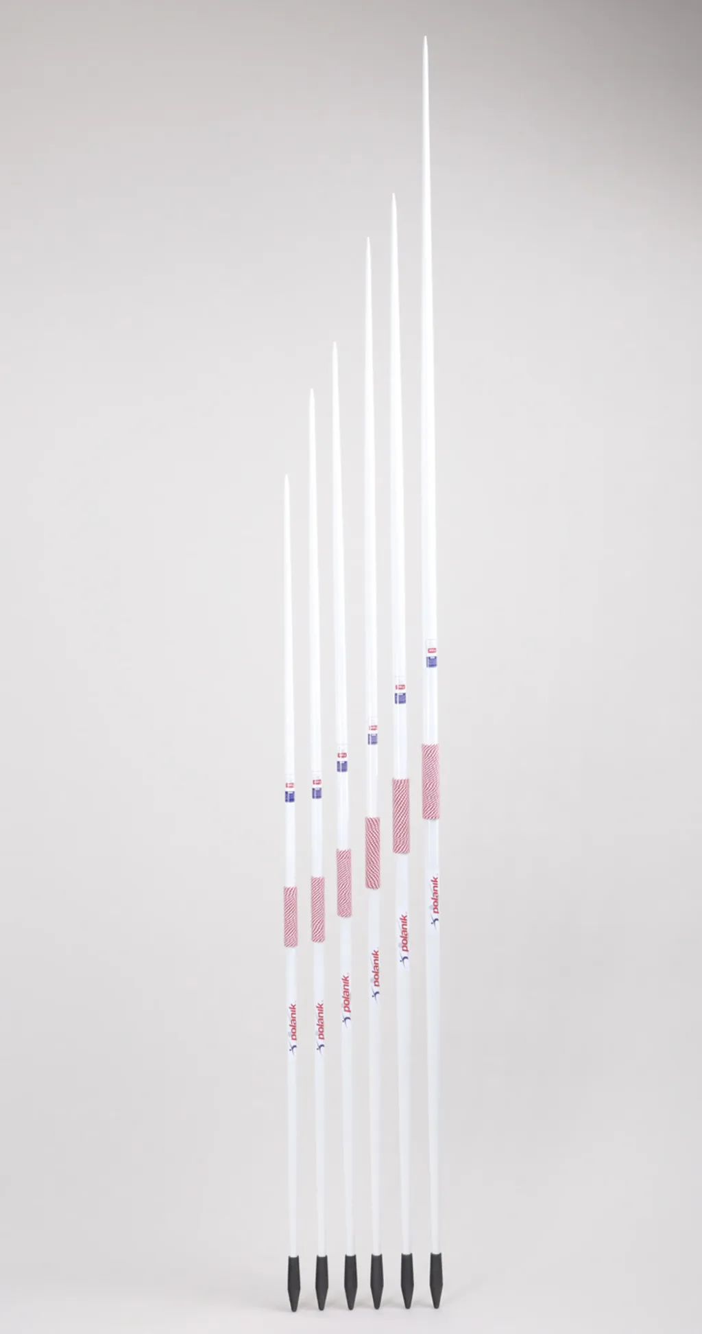Six white javelins of increasing length with red hand grips, black rubber heads, and polanik printed on the shafts.