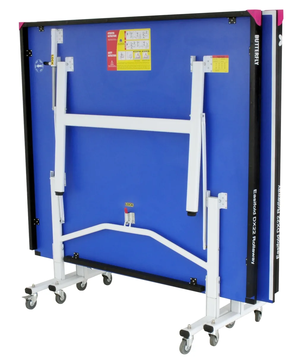 Blue foldaway table tennis table stored upright on light silver legs and undercarriage with magenta corner pieces and caster wheels, label reads LOCK.