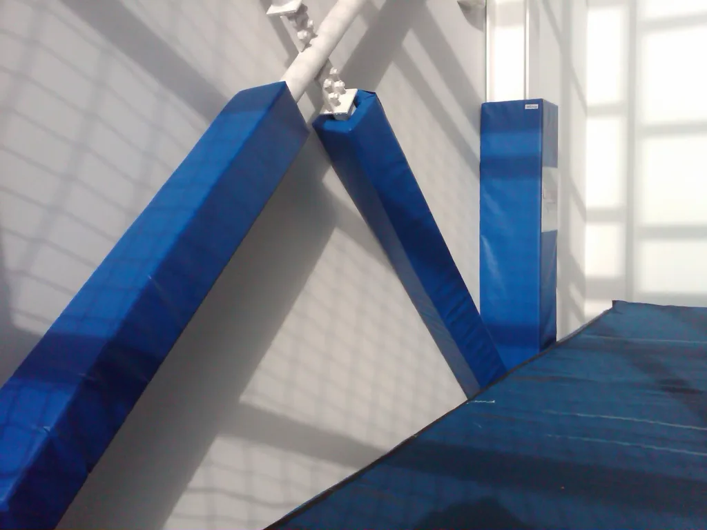 Three royal blue PVC-covered square post pads attached to diagonal metal posts beside a blue floor mat.