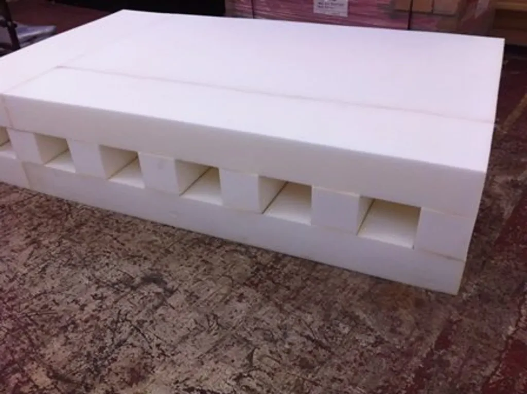 Replacement foam for high jump and pole vault with castellated rectangular hollow cells visible along the side, resting on a textured floor.