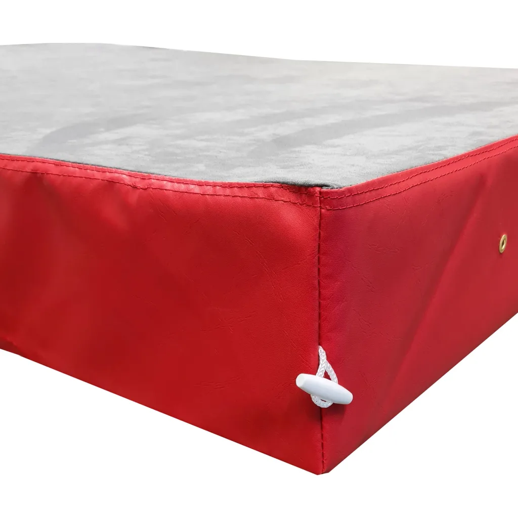 Crash mat with grey jersey fabric top, red PVC sides, stitched corner, white pull-cord toggle and brass grommet.