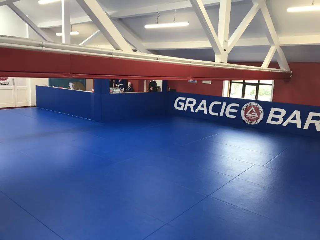 Promat Contest BJJ mat in blue covering a gym floor with white "GRACIE BAR" wall lettering.