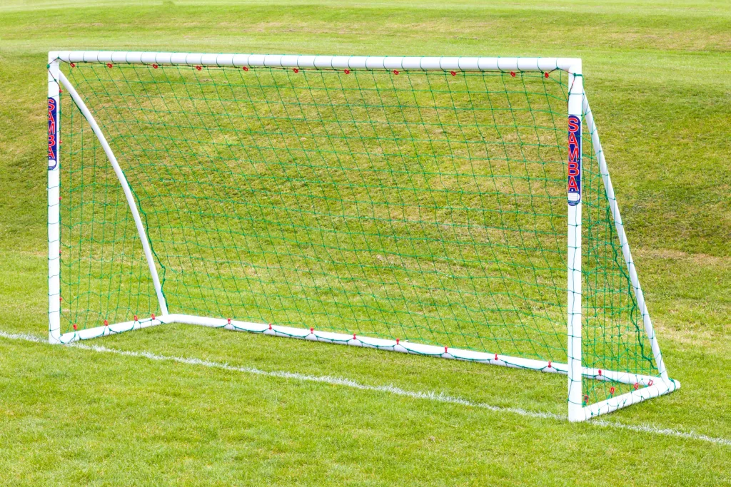 White freestanding training goal with green netting and SAMBA printed on the uprights, set on grass.