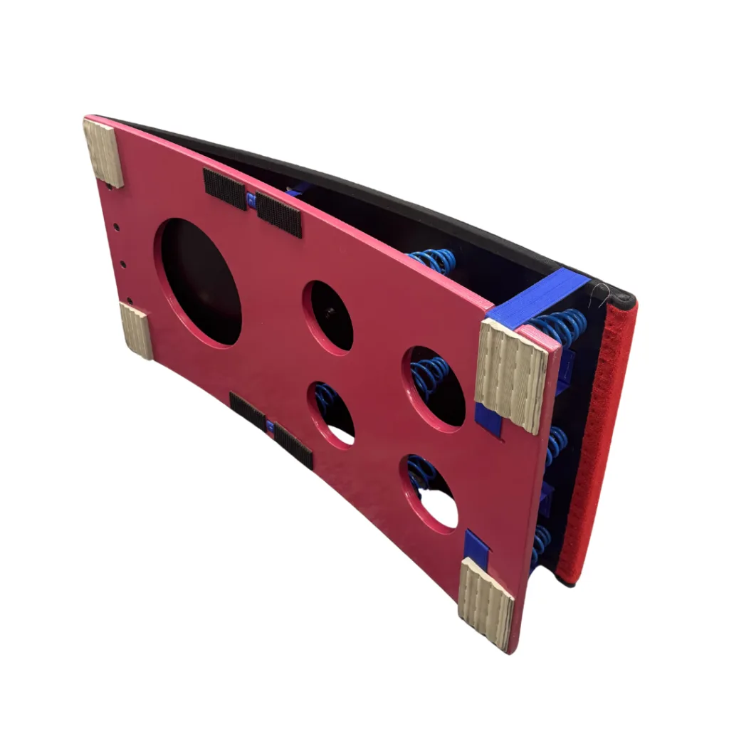 Competition springboard with pink face panel featuring circular cutouts, blue springs visible inside, wooden corner blocks and red end pad.