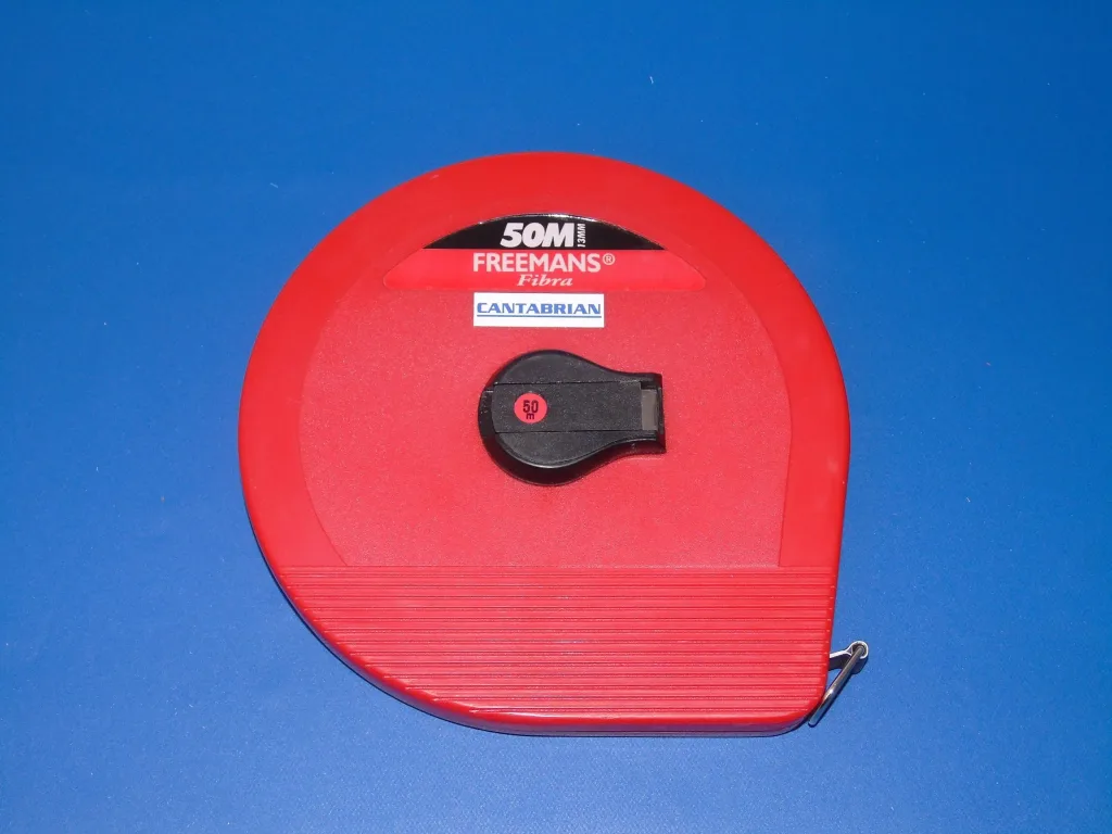 Red cloth measuring tape in a red circular case with a black winding knob and printed label, on a blue background.