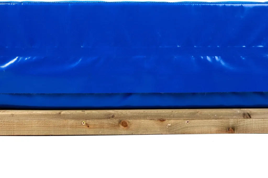 Blue landing mat resting on a treated wooden base platform section with visible screw heads and wood knots.