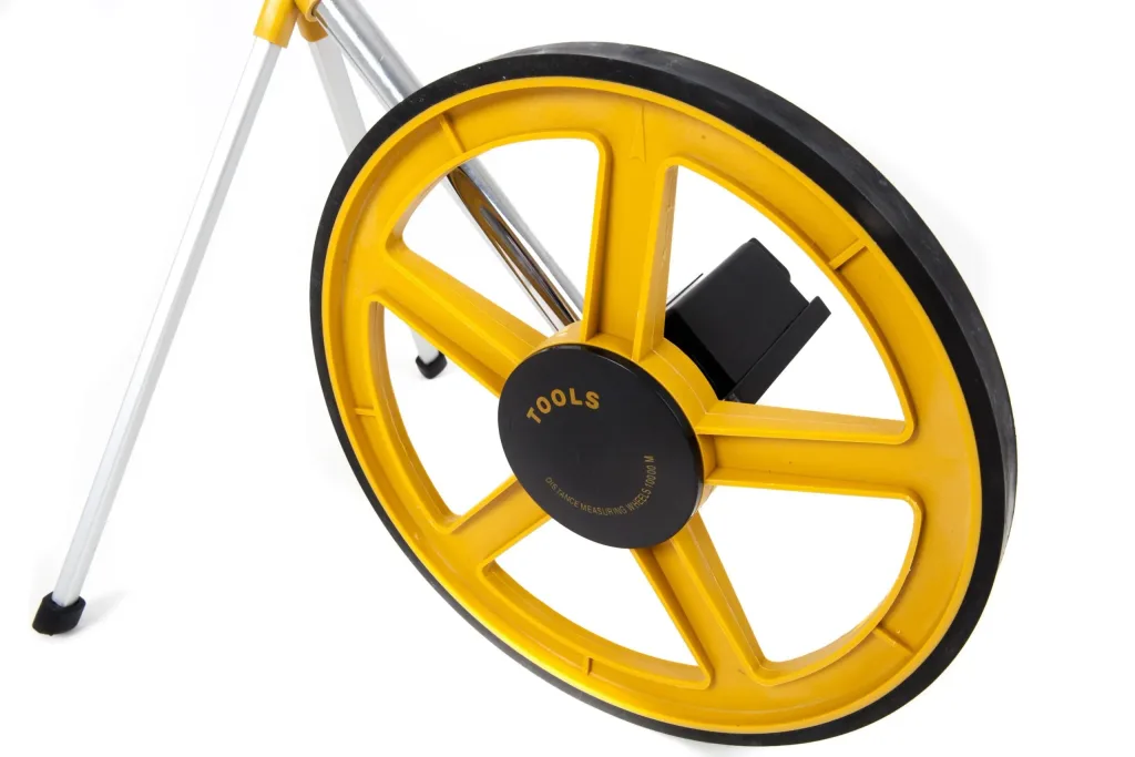 Yellow measuring wheel with black rubber rim and center housing labeled TOOLS, attached to a folding silver handle.