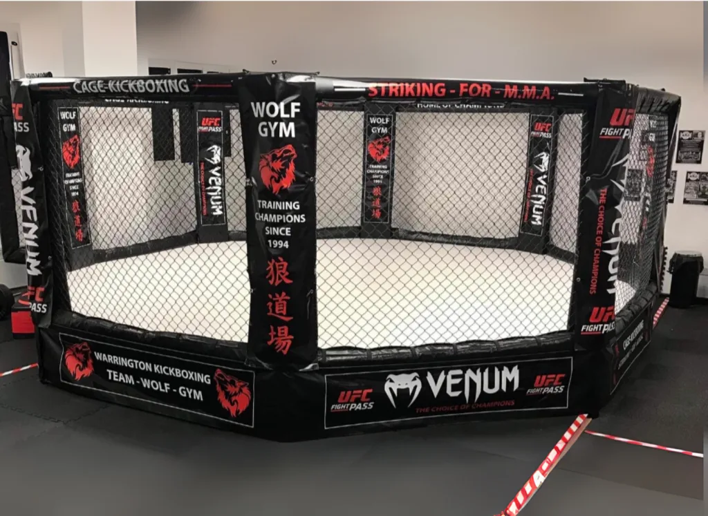 Platform training cage with steel frame, raised deck and mesh enclosure, padded post reading "Wolf Gym Training Champions Since 1994".