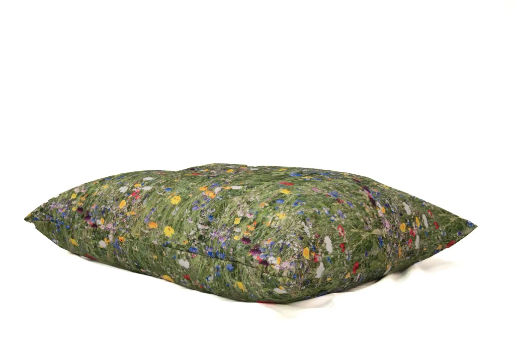 Large floor cushion with a 100% polyester nature print cover depicting green grass and scattered yellow, red, blue and white wildflowers.