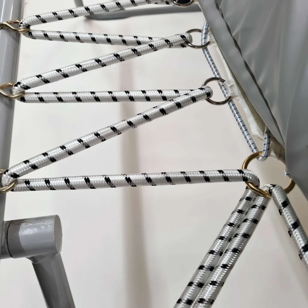 Mini Tramp with white ropes patterned in black attached by metal rings to a grey zinc-plated steel frame and grey nylon-reinforced PVC padding.