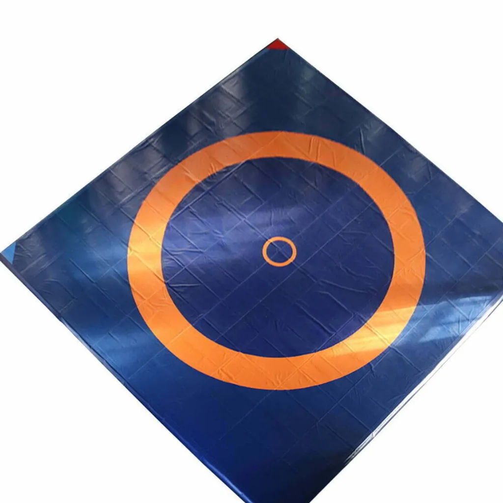 Blue vinyl wrestling mat cover with an orange outer circle and small orange central circle, showing stitched module seams.