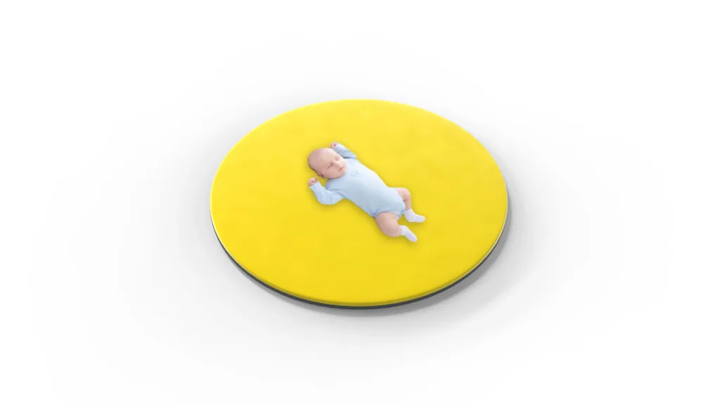 Round yellow baby play mat with a sleeping infant in a light blue onesie centered on it.