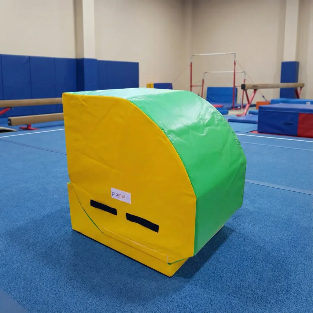 Green curved-top and yellow high-density PU foam tumbler with flame-retardant PVC cover, label 'promat', and black handles on a blue gym floor.