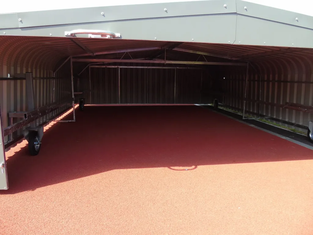 A galvanised welded steel wheel-away cover with electro-galvanised cladding opened to reveal a red track surface and interior wheels.