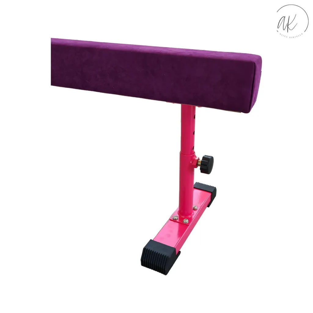 Purple padded wood balance beam with suede cover on pink adjustable metal legs and black rubber feet, circular logo reading "ak ALICE KINSELLA".