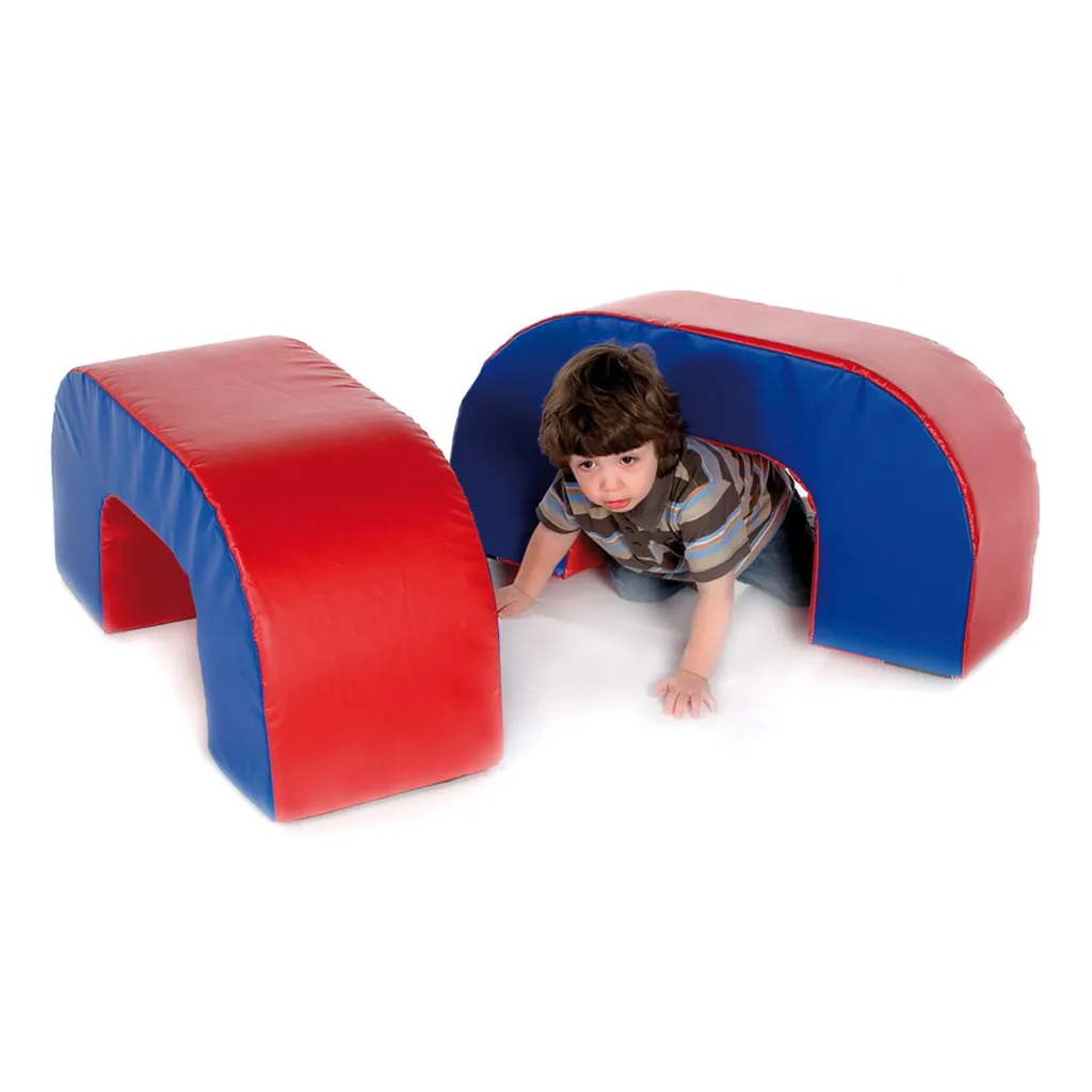 Child in a striped shirt crawling through a padded red and blue soft-play arch with a matching arch nearby.