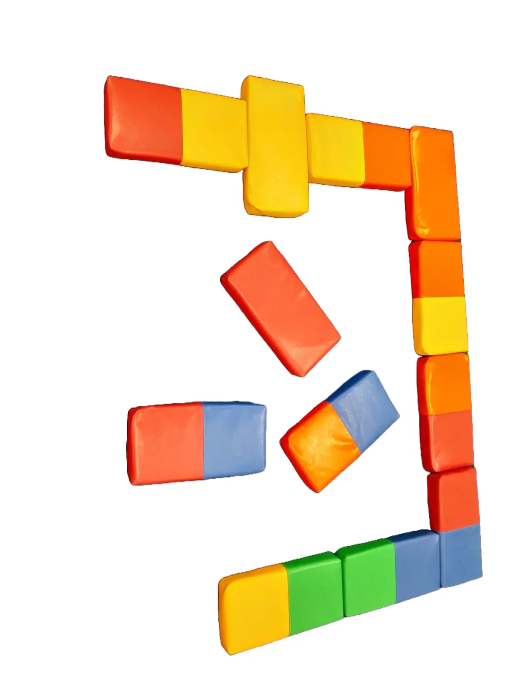 High-density foam domino blocks in a mixture of four colours scattered and forming a corner on a white background.