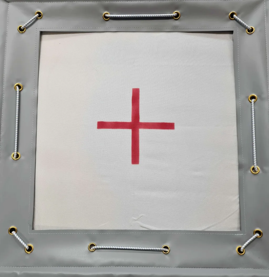 Square white tramp bed with a red plus sign centered, set in a grey padded frame with gold grommets and white striped elastic cords.