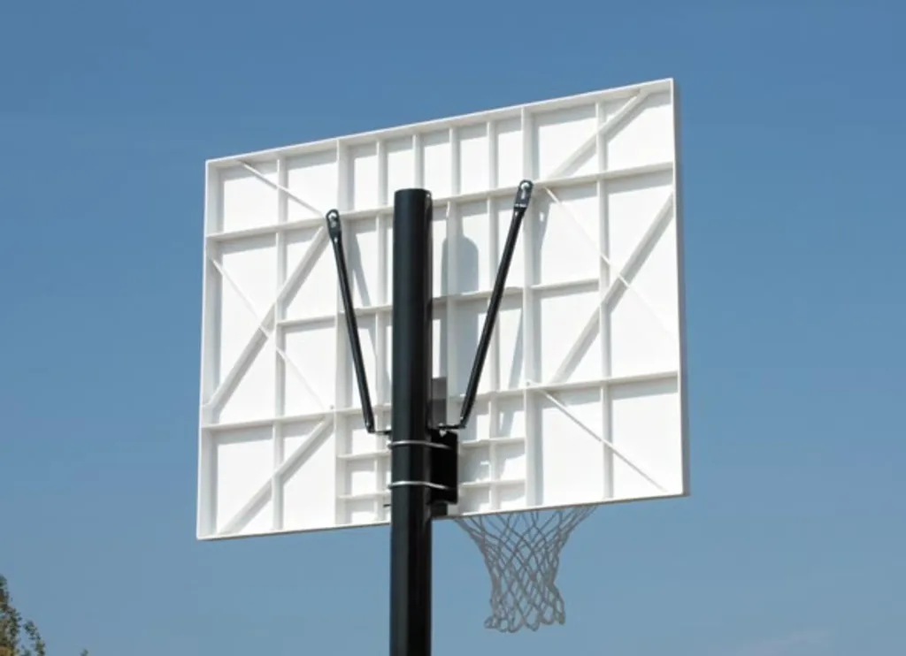 White polypropylene rectangular backboard with internal bracing mounted on a black pole and black support arms, with a hanging rim and net against blue sky.