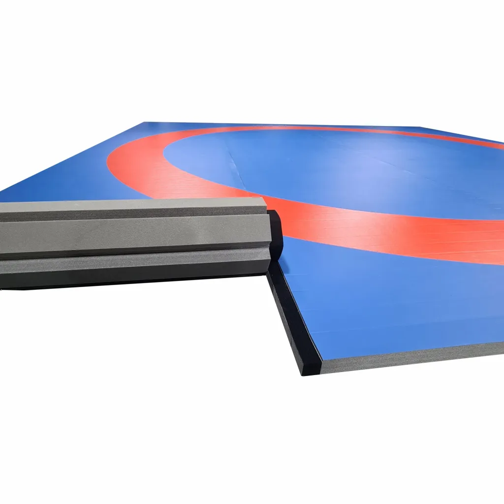 Blue wrestling mat with a red circle, smooth PVC surface, and a gray high-density cross-link foam rolled edge with a black border.