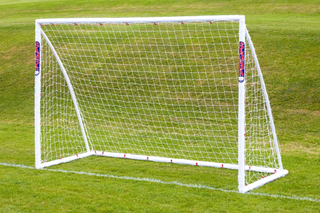 White high-impact uPVC freestanding trainer goal with net and SAMBA text on posts, positioned on green grass.