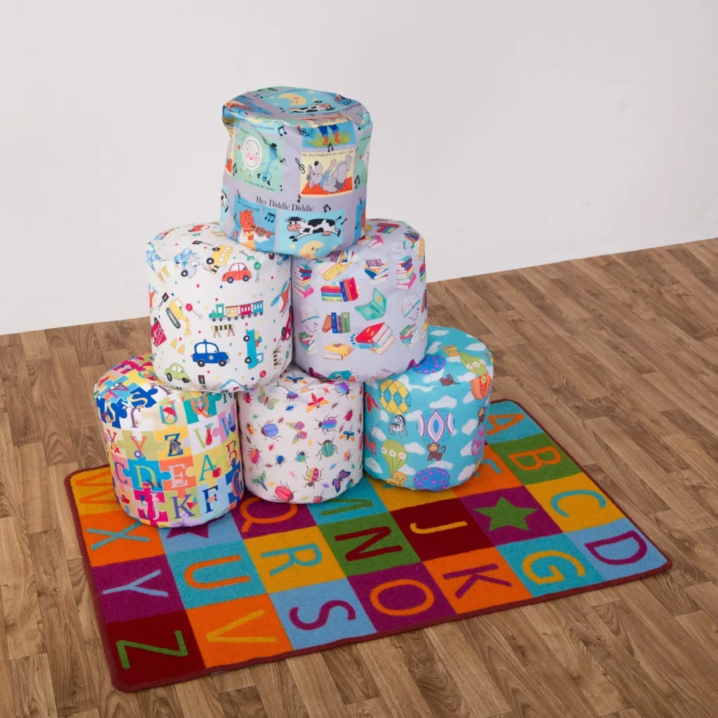 Six educational fabric child bean sitting pods stacked on a colorful alphabet rug on a wood floor.