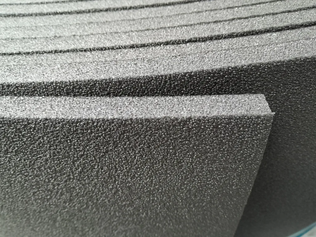 Stacked textured foam sheets with a pebble-like surface and a visible straight cut edge, shown as an underlay for sprung floors.