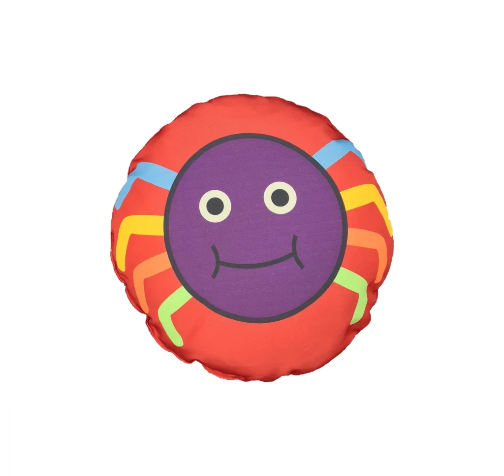 Round red children's scatter cushion with a purple smiling spider face and blue, yellow, orange and green legs.