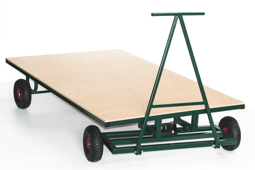 Large flat bed trolley with steel construction, flat deck, four wheels, a triangular pull handle and towing eye for tractor.