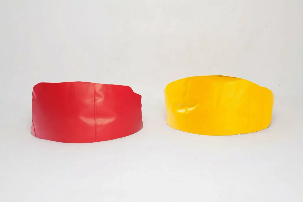 Two child pie bean bag seats in faux leather, one red and one yellow, placed side by side on a plain white background.
