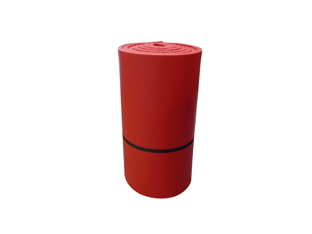 Rolled red agility mat with leather-effect PVC cover over recycled chipfoam, secured by a black strap and showing a spiral roll top.