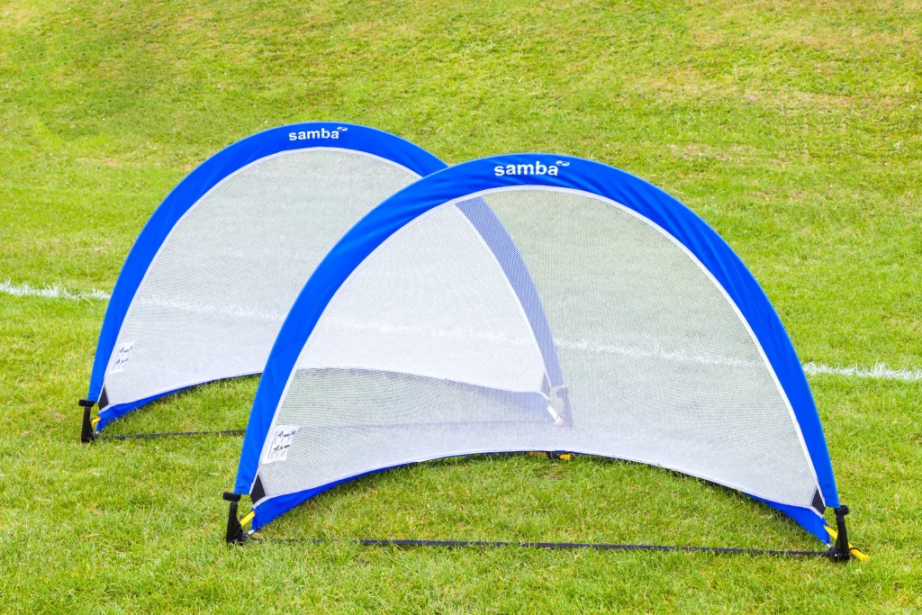 Two blue pop-up goals with 'samba' printed on their top edges set on a grassy field.
