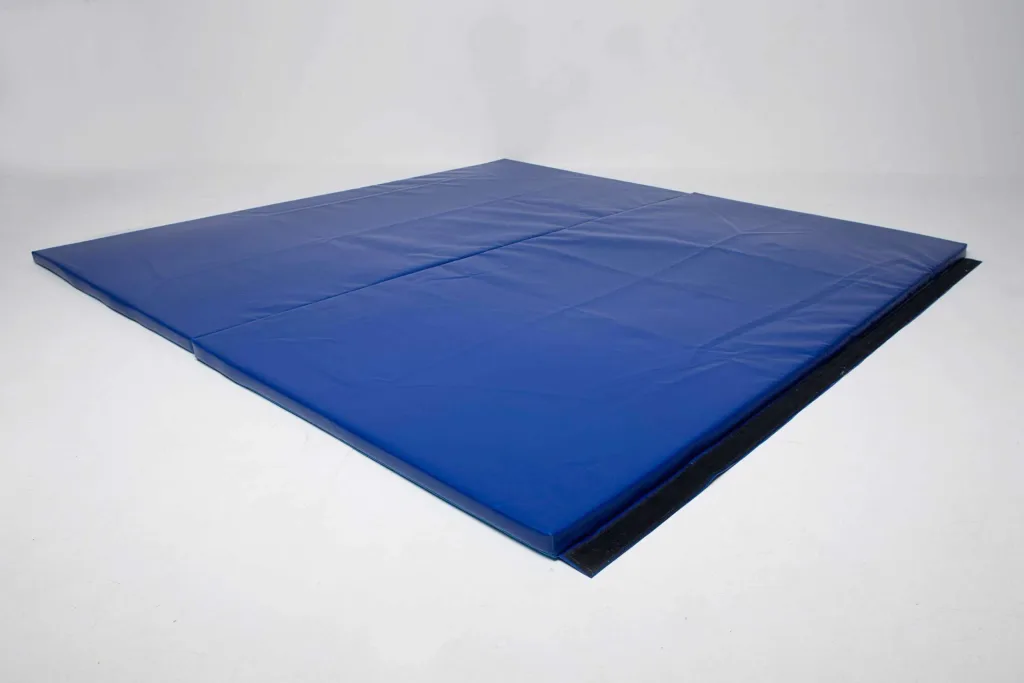 Blue heavy-duty PVC mat with chipfoam core, stitched seams and black anti-slip strip, folded in two on a white floor.