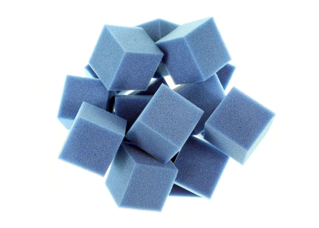 A loose pile of blue foam cubes on a white background.