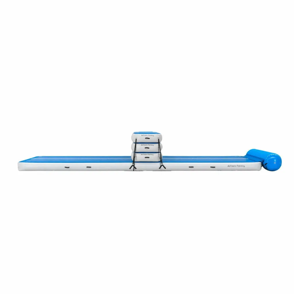 Blue and white inflatable gymnastics runway with three stacked, strapped blocks at center, rolled blue end, and text "AirTrack Factory" visible.