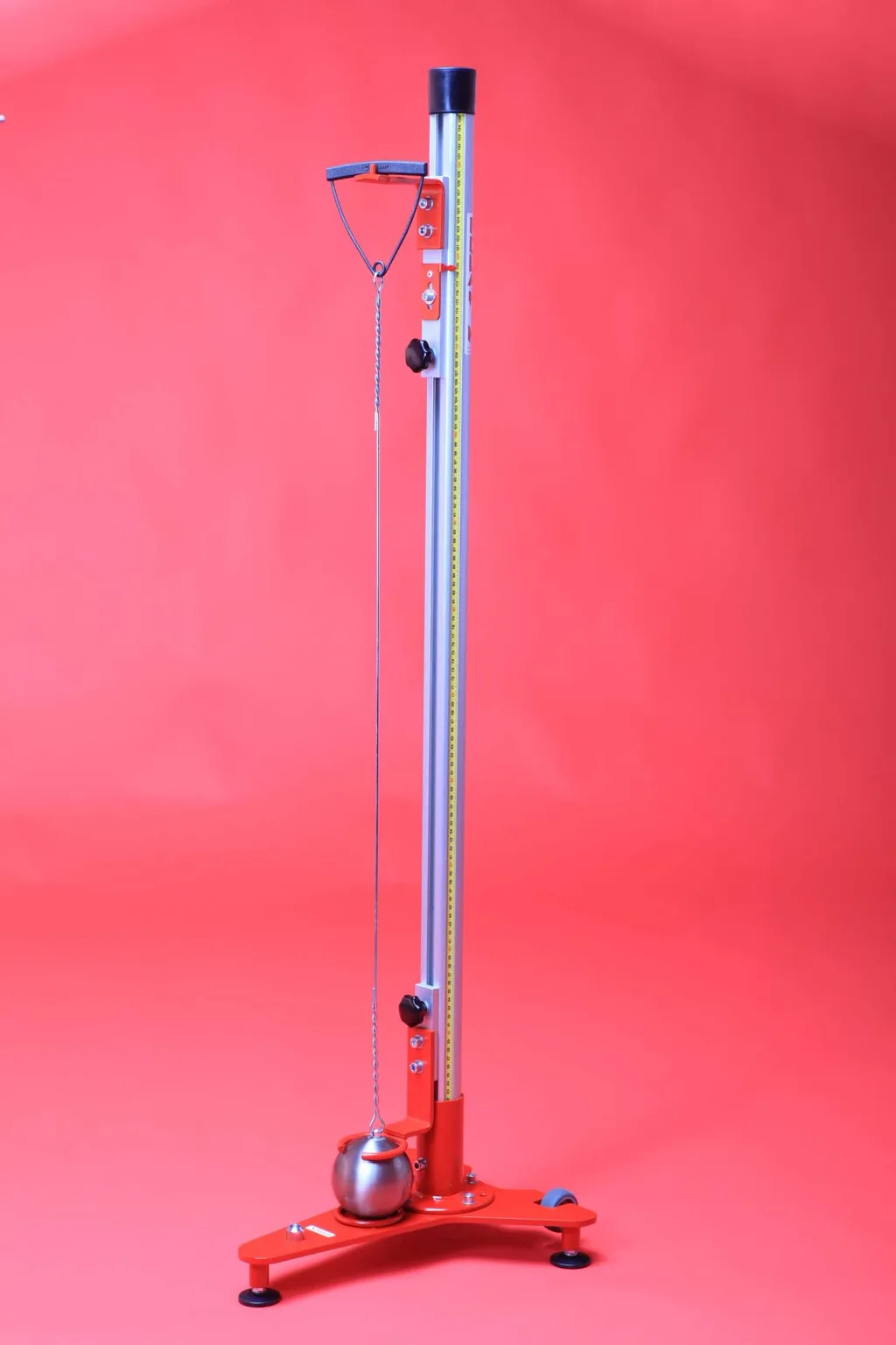Tall aluminium and steel measuring stand with a vertical ruler, hanging chain and metal hammer resting on a red tripod base.