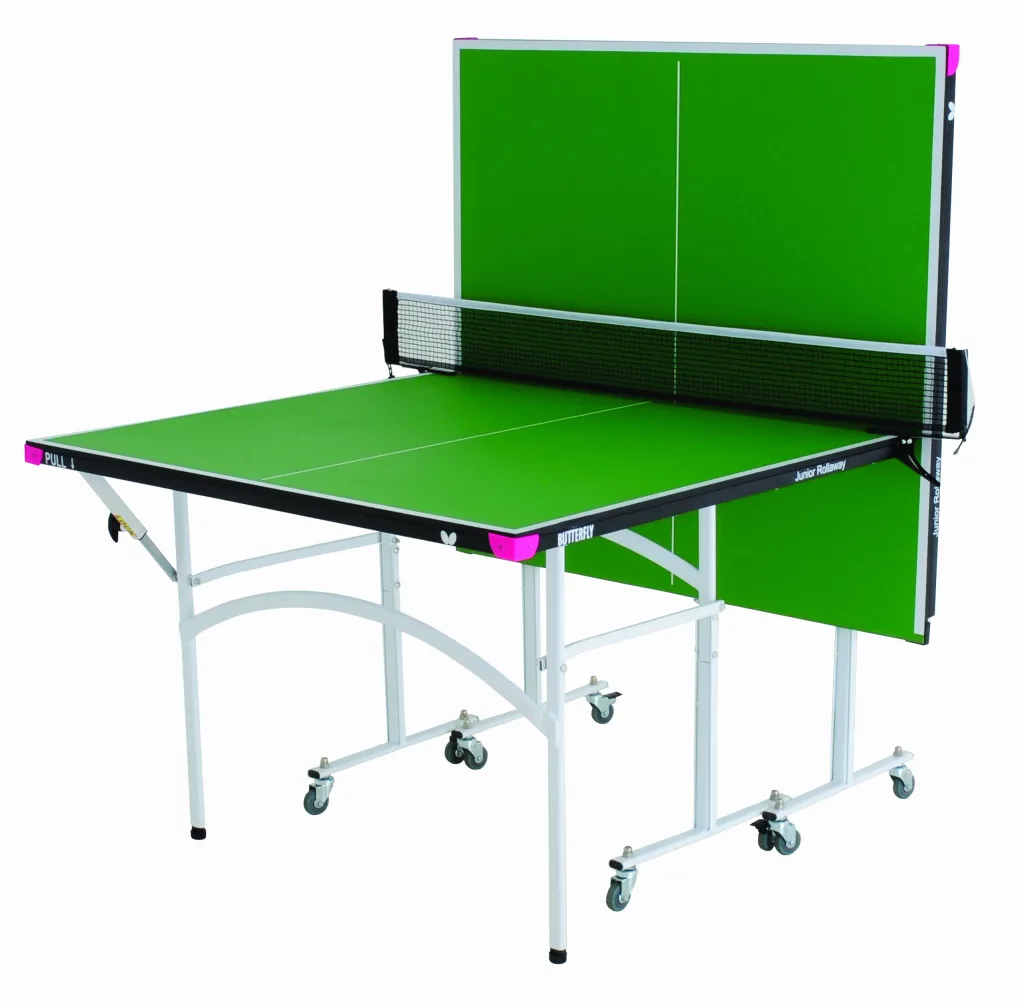 Green half-size table tennis table, one half folded upright, white legs, magenta corners, black net and casters, labelled Junior Rollaway.
