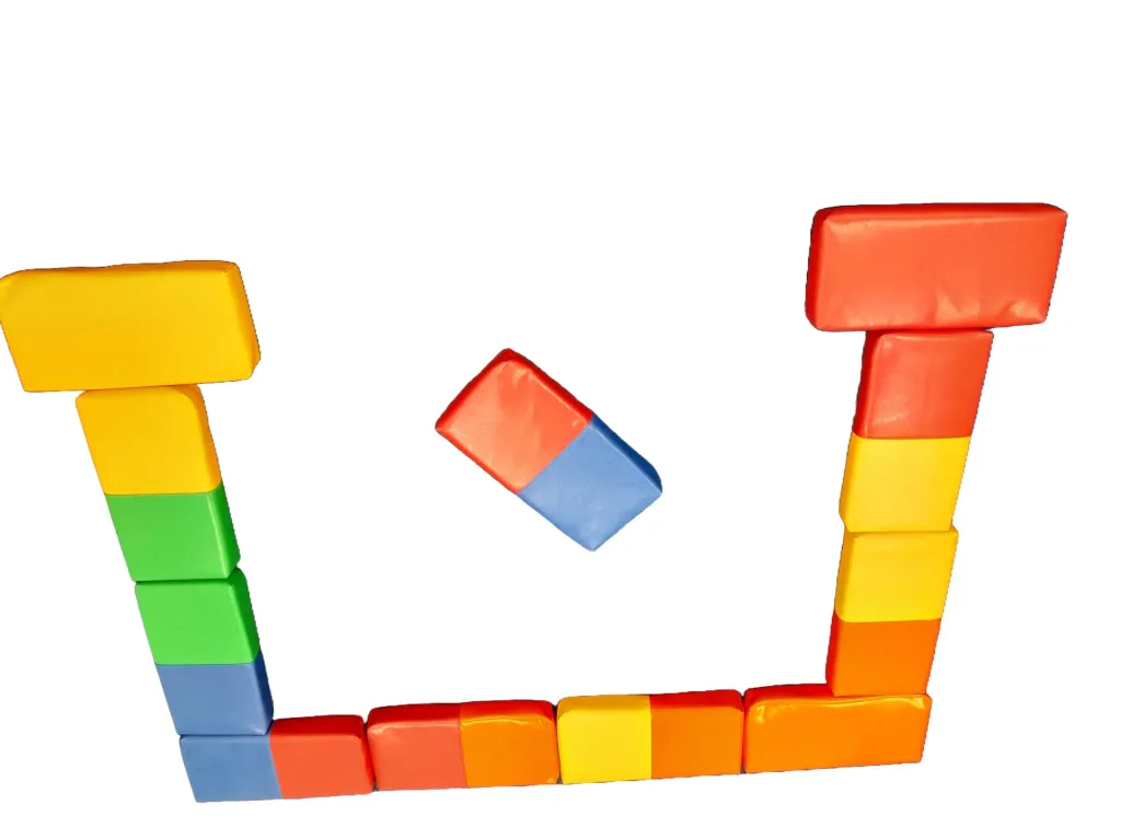 A U-shaped arrangement of foam dominoes in mixed colors with stacked columns on each side and one tile mid-air.