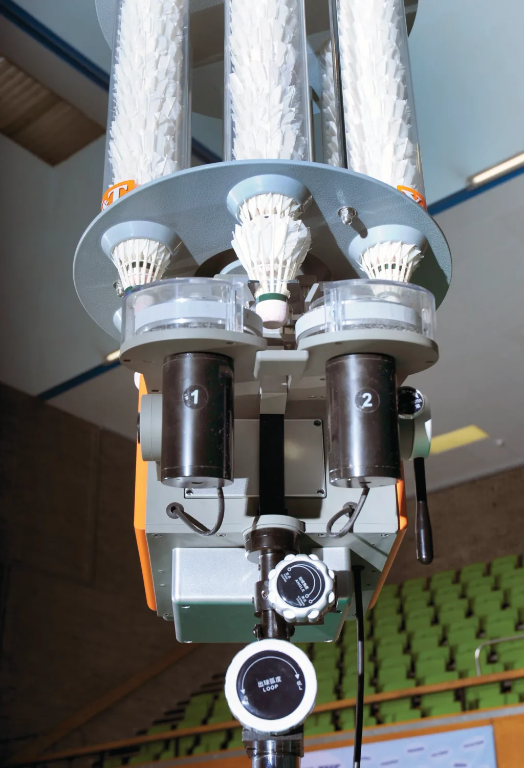 Badminton shuttle feeder with three vertical tubes of white shuttlecocks, two feed ports numbered 1 and 2, and a round control labeled LOOP.