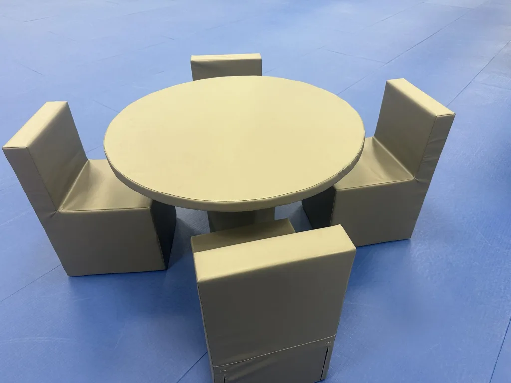 Round foam table surrounded by four single foam chairs with tear resistant PVC covers on a blue mat.