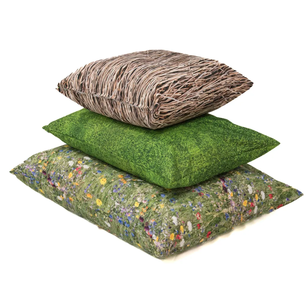 Stack of three nature-print large floor cushions with a top twig pattern, a middle green grass print, and a bottom wildflower meadow print.