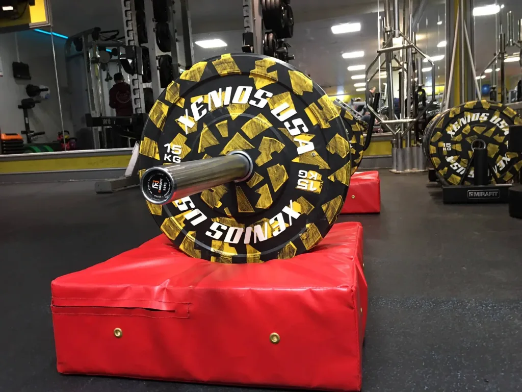 Weightlifting drop pad in fire-retardant PVC supporting a barbell with a weight plate marked 15 KG.